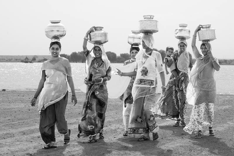 Nature-based solution for quenching thirst in the driest place of India - Women  and girls returning home with pots full of cool and sweet drinking water from Viprasar, a rainfed pond in Thar Desert, Jaisalmer district, Rajasthan